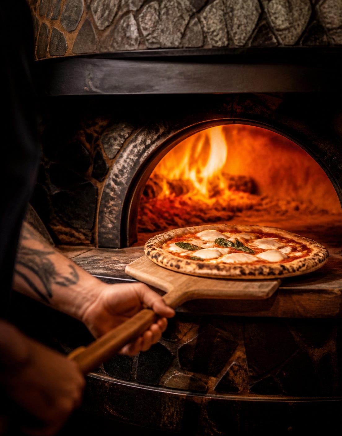 Pizza i den glödande vedugnen
